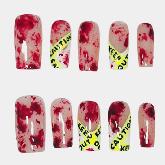 Handmade crime scene press on nails with red splatter and yellow caution tape